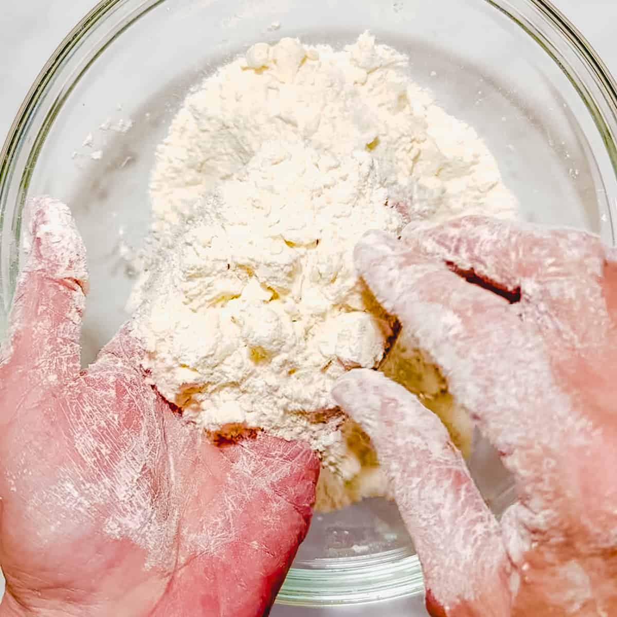 using fingers to check for butter size and consistency in biscuit dough.