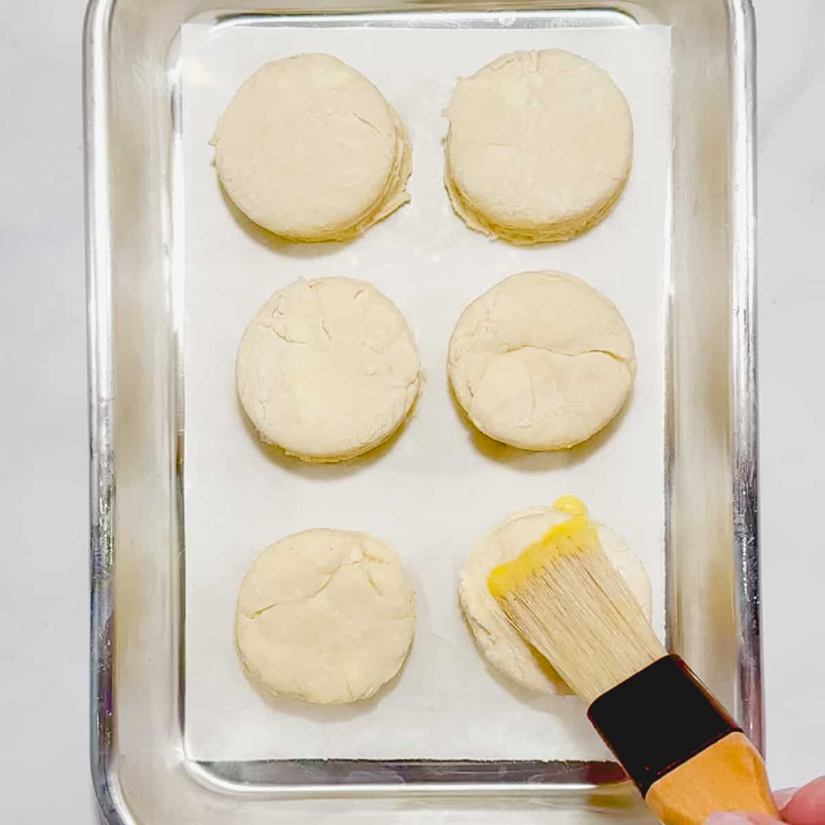 brushing an egg wash on unbaked biscuits.