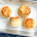 Four biscuits on a parchment lined sheet pan.