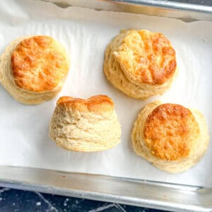 Four biscuits on a parchment lined sheet pan.