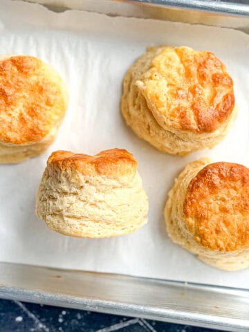Four biscuits on a parchment lined sheet pan.