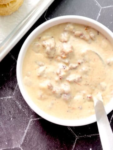 Sausage gravy in a bowl with a silver ladle.