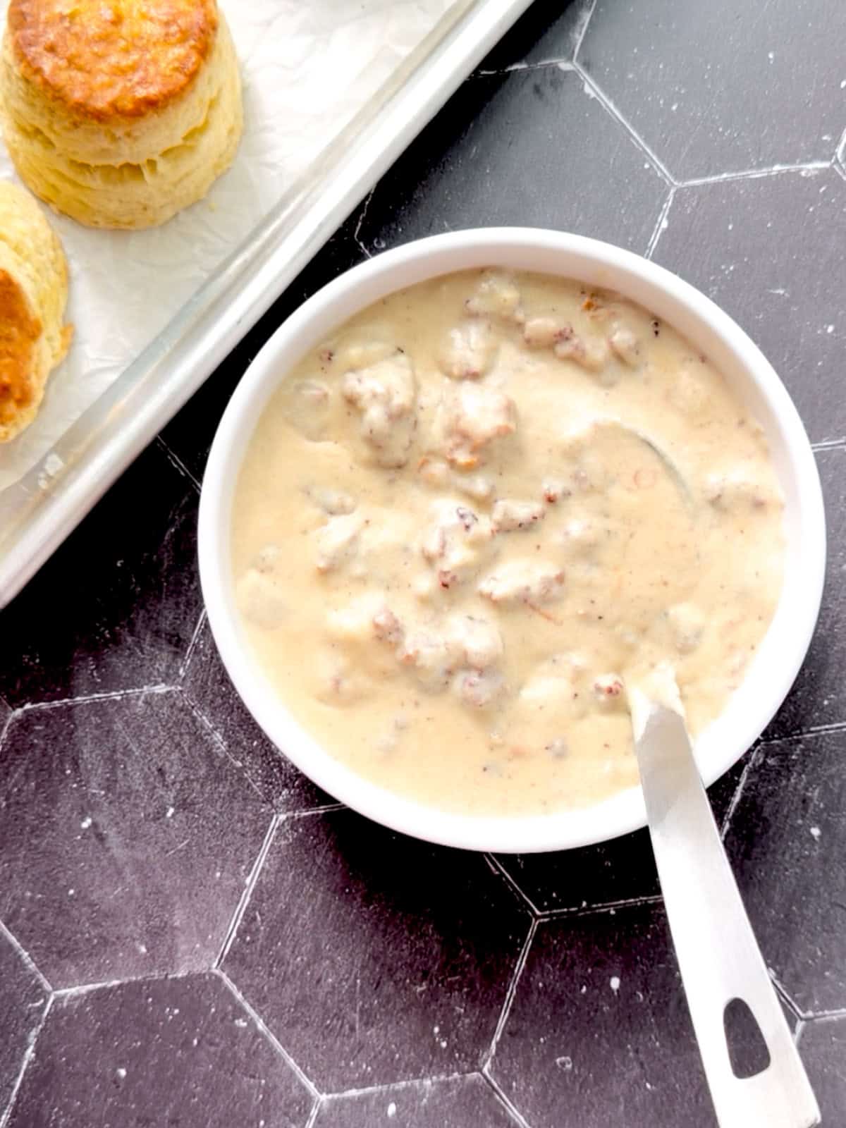 Sausage gravy in a bowl with a silver ladle.
