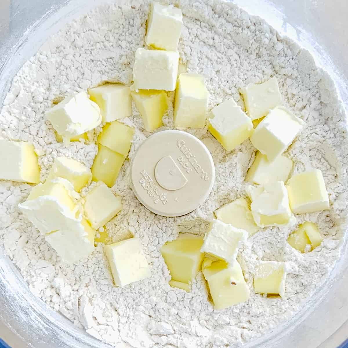 adding butter cubes to biscuit dry ingredients in food processor.