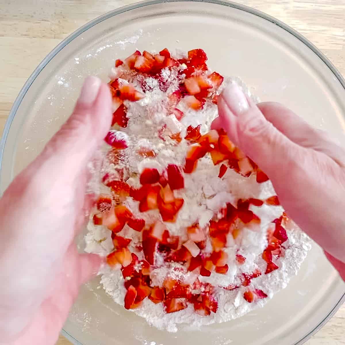 tossing diced strawberries with biscuit dough ingredients.