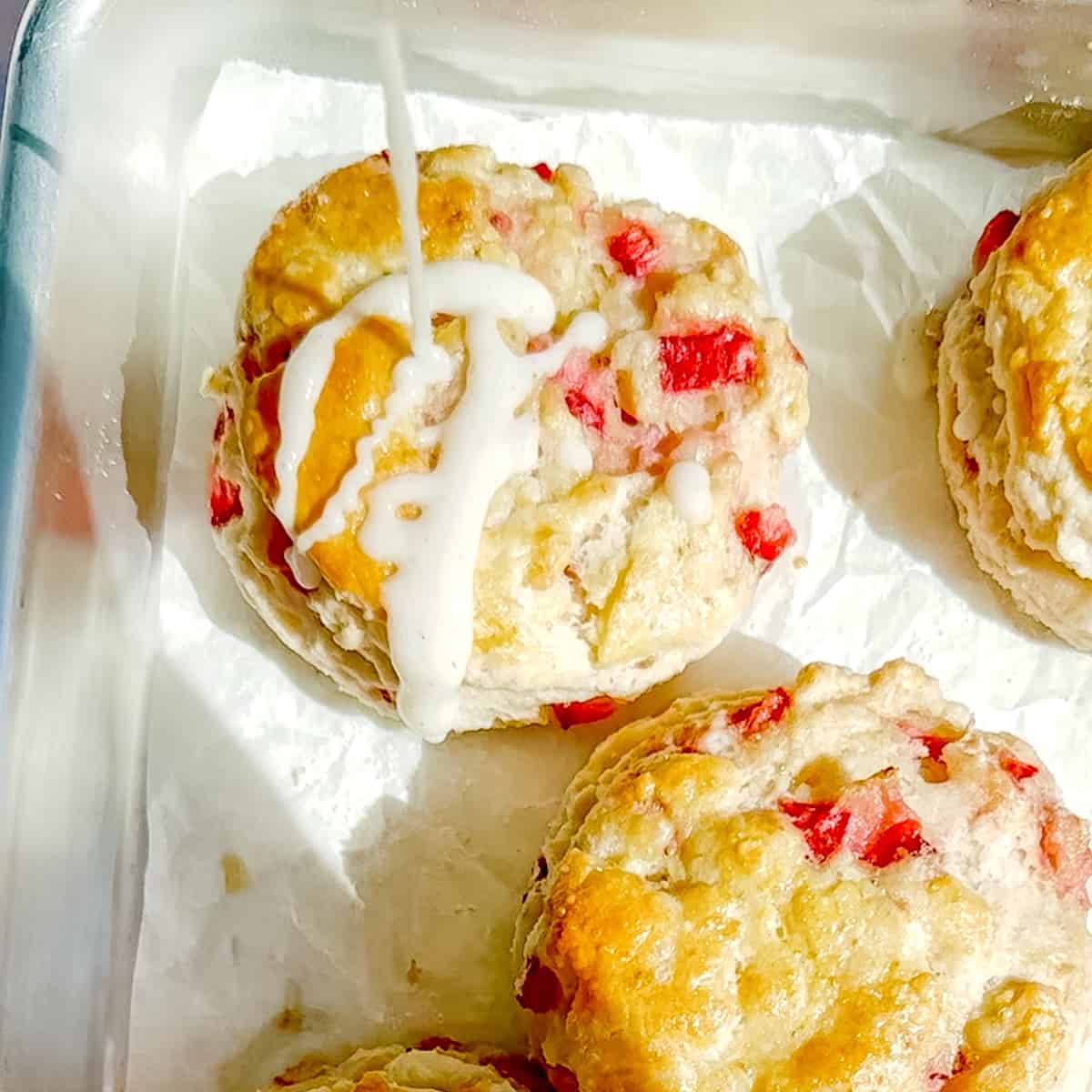 drizzling icing on a strawberry biscuit.