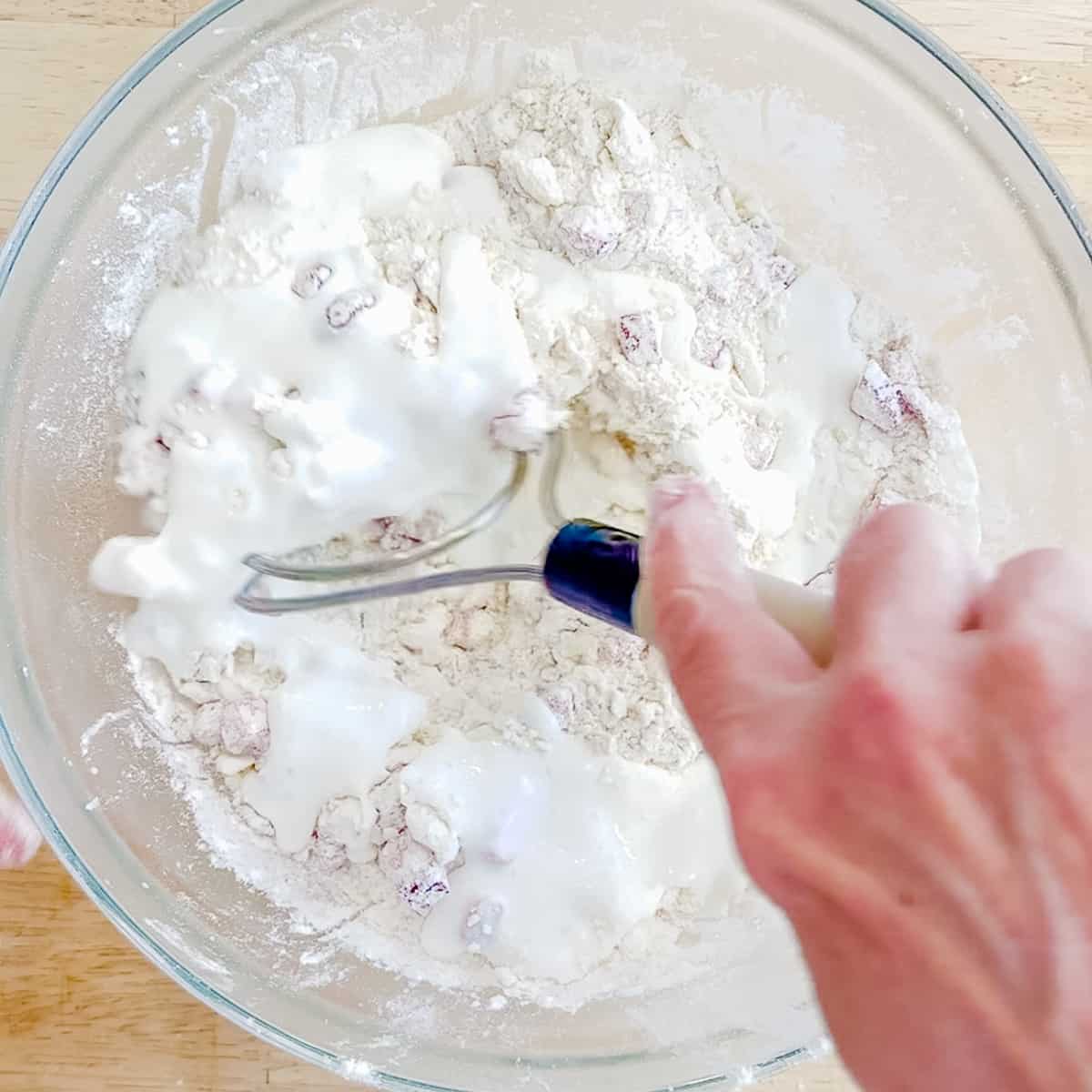 mixing buttermilk into strawberry biscuit ingredients.