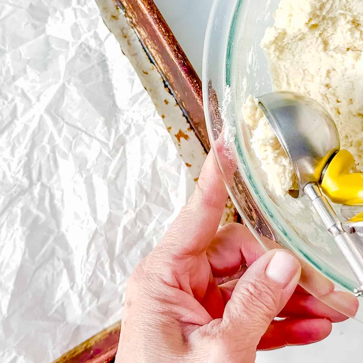 using an ice cream scoop to portion biscuit dough.