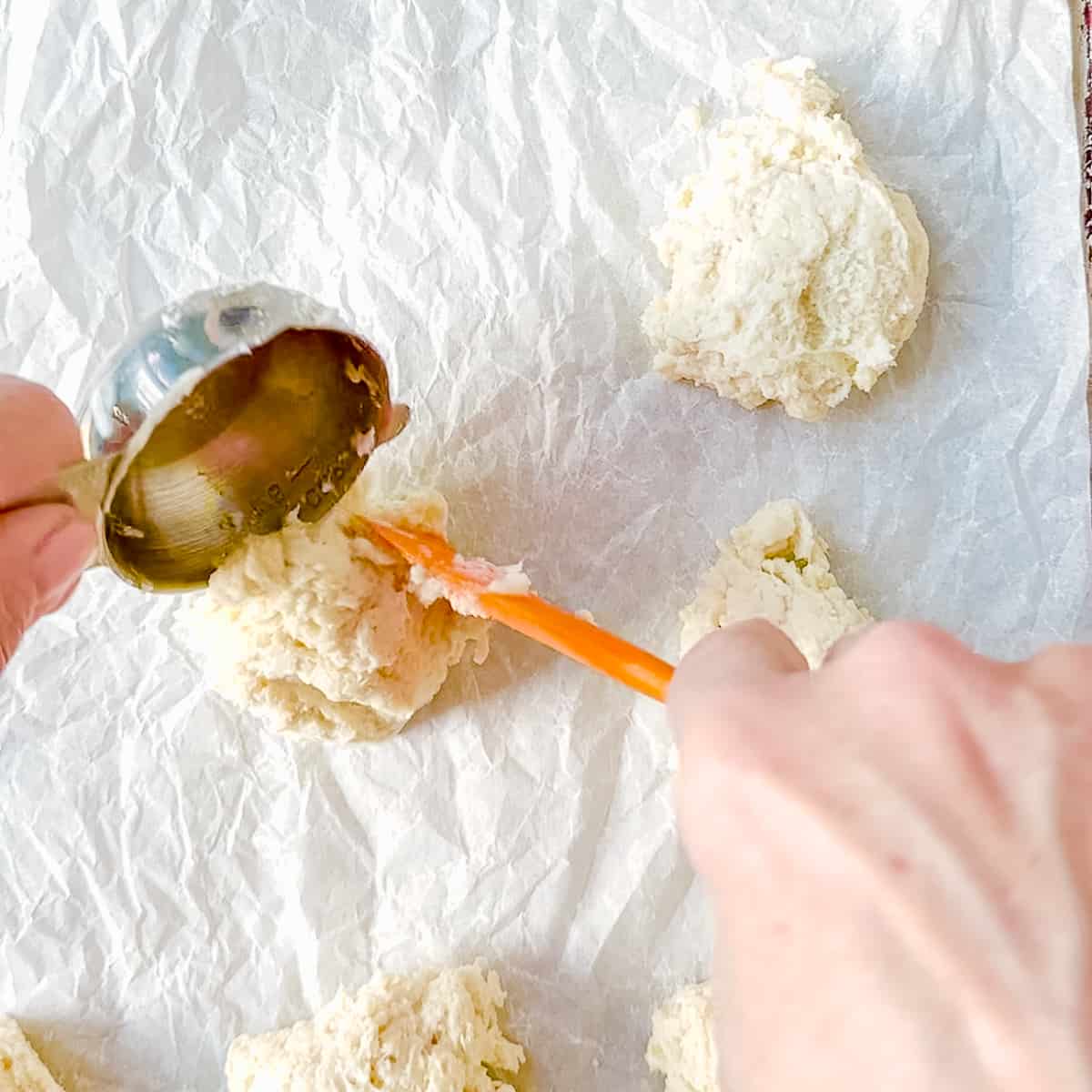 using a measuring cup to portion biscuit dough.