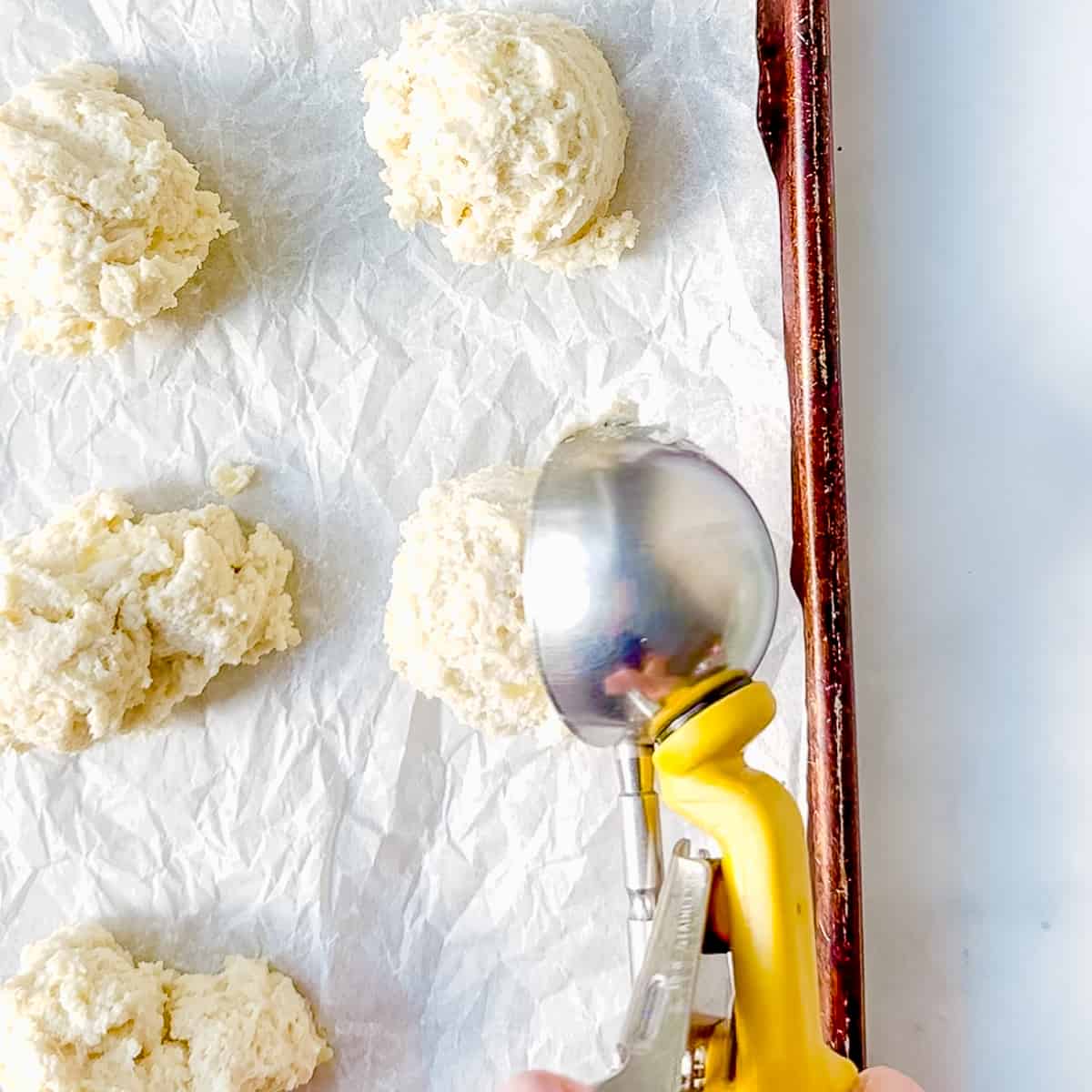 using an ice cream scoop to portion drop biscuit.