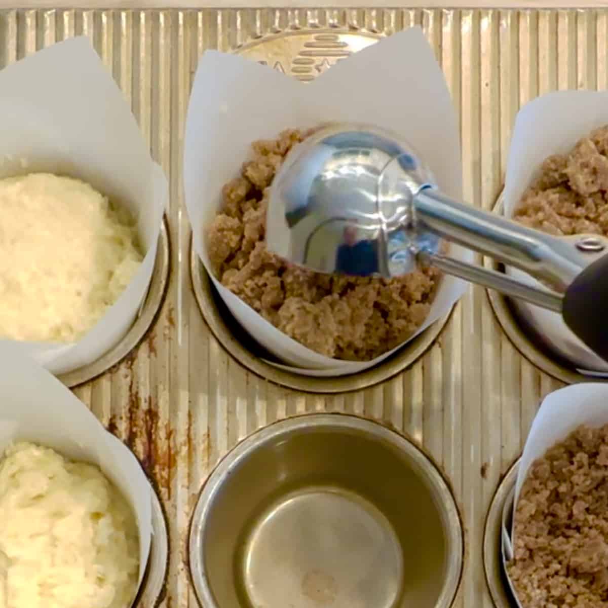 closeup of adding crumb topping to muffin batter.