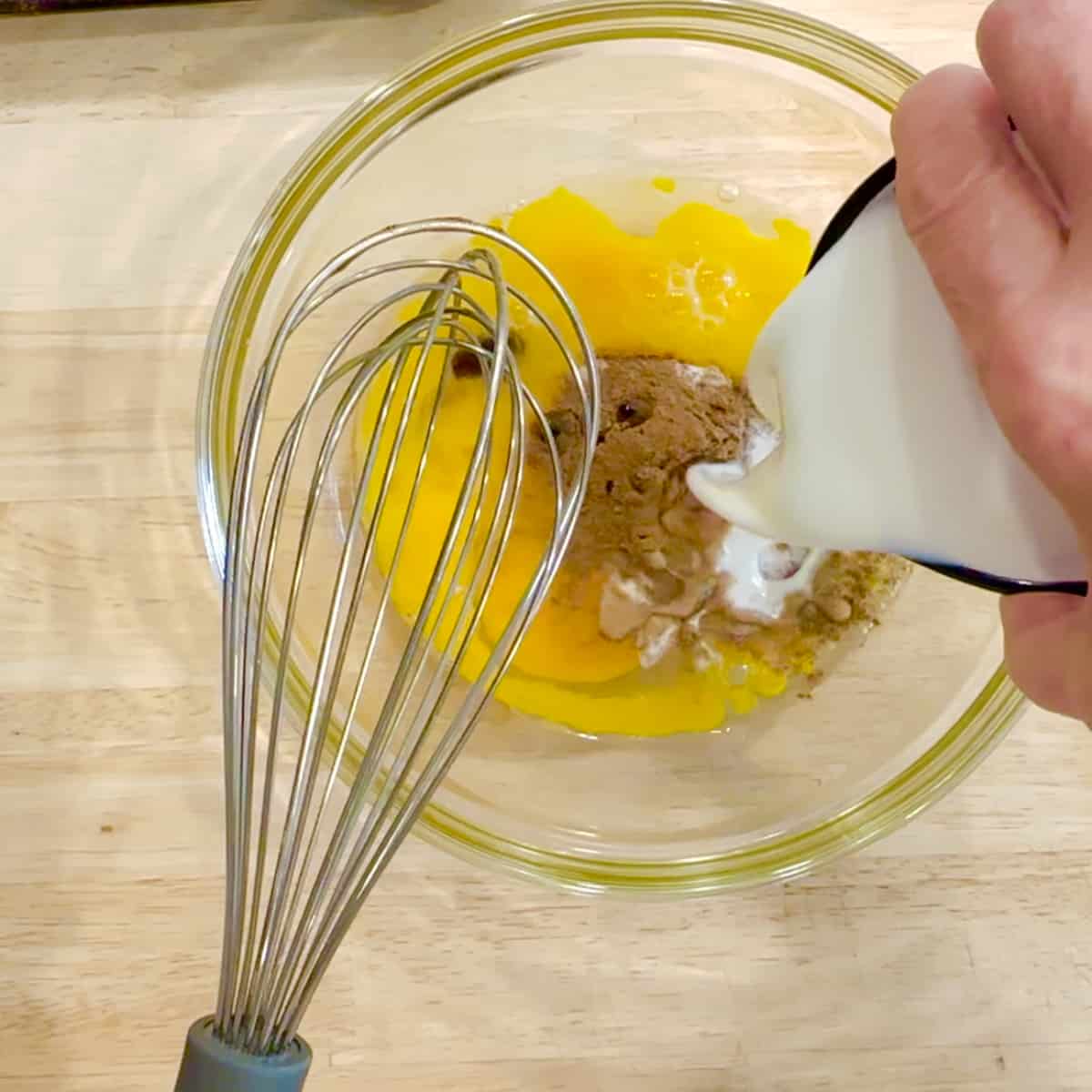adding milk to whisked eggs and spices for french toast.