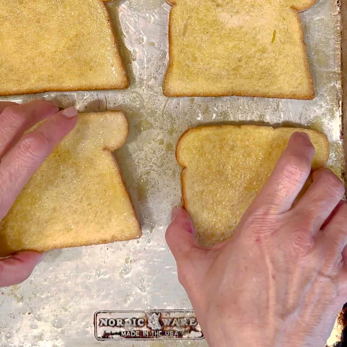 placing custard soaked bread slices on a sheet pan with melted butter.