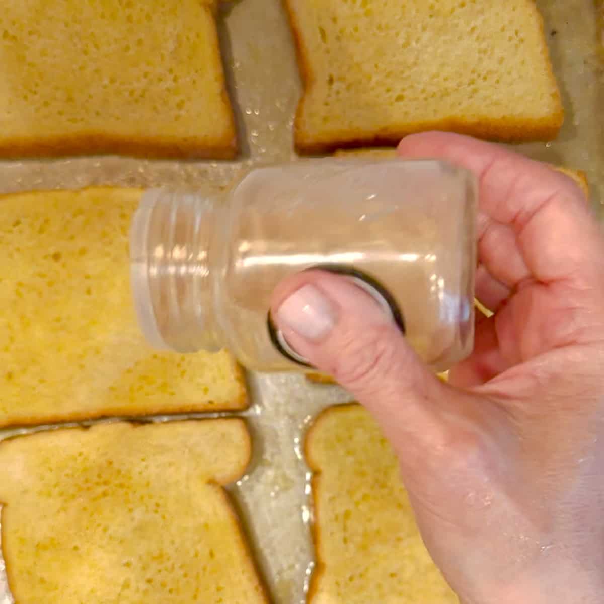 sprinkling cinnamon sugar on sheet pan french toast.