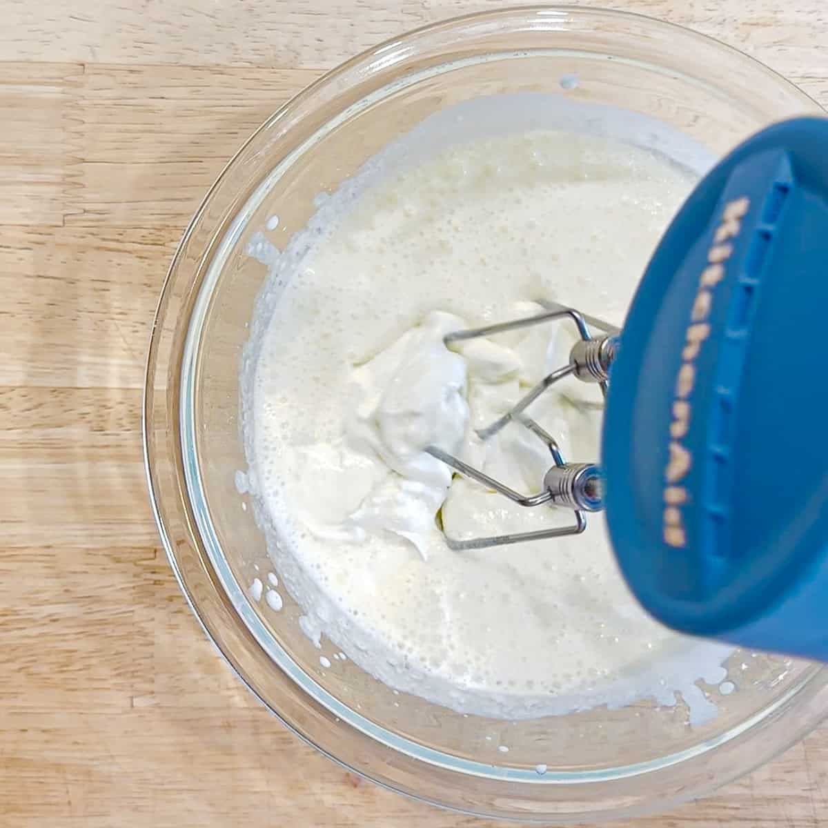 mixing greek yogurt into softly whipped cream.