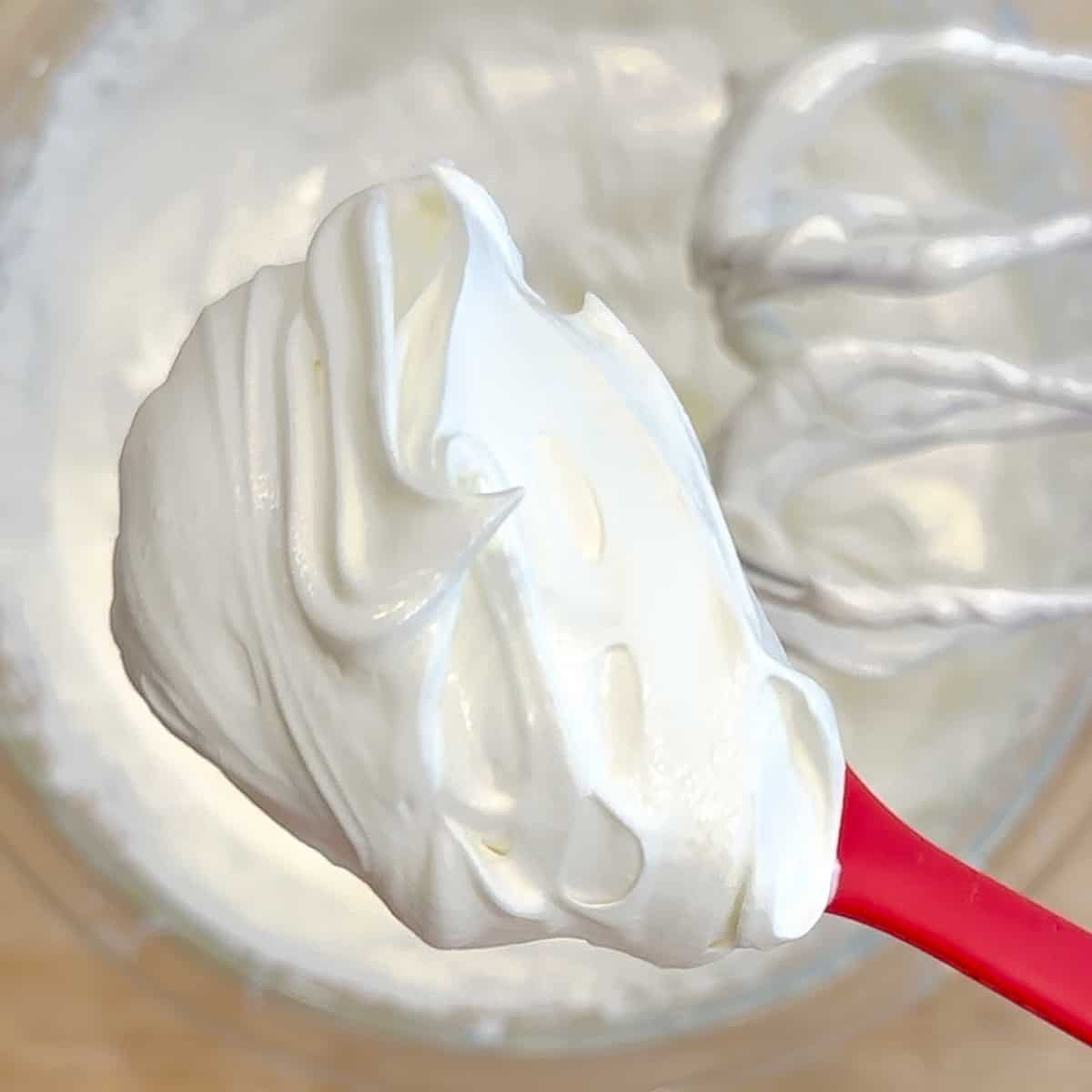 whipped greek yogurt cream on a red spatula.