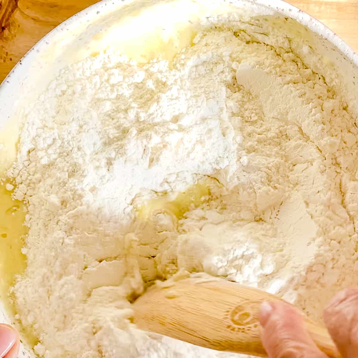 stirring dry banana nut muffin ingredients into wet ingredients.