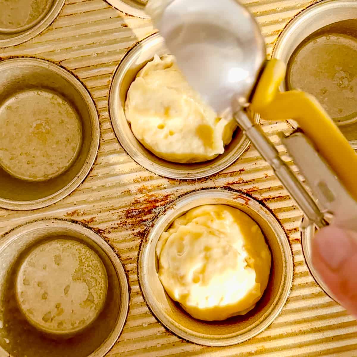 scooping banana nut muffin batter into a muffin pan.