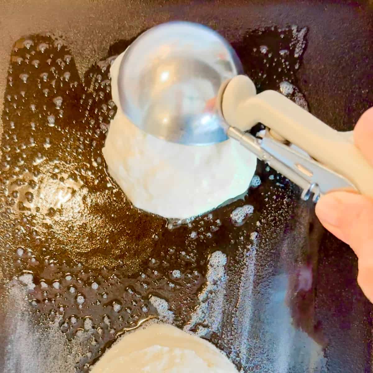 scooping pancake batter onto a griddle.