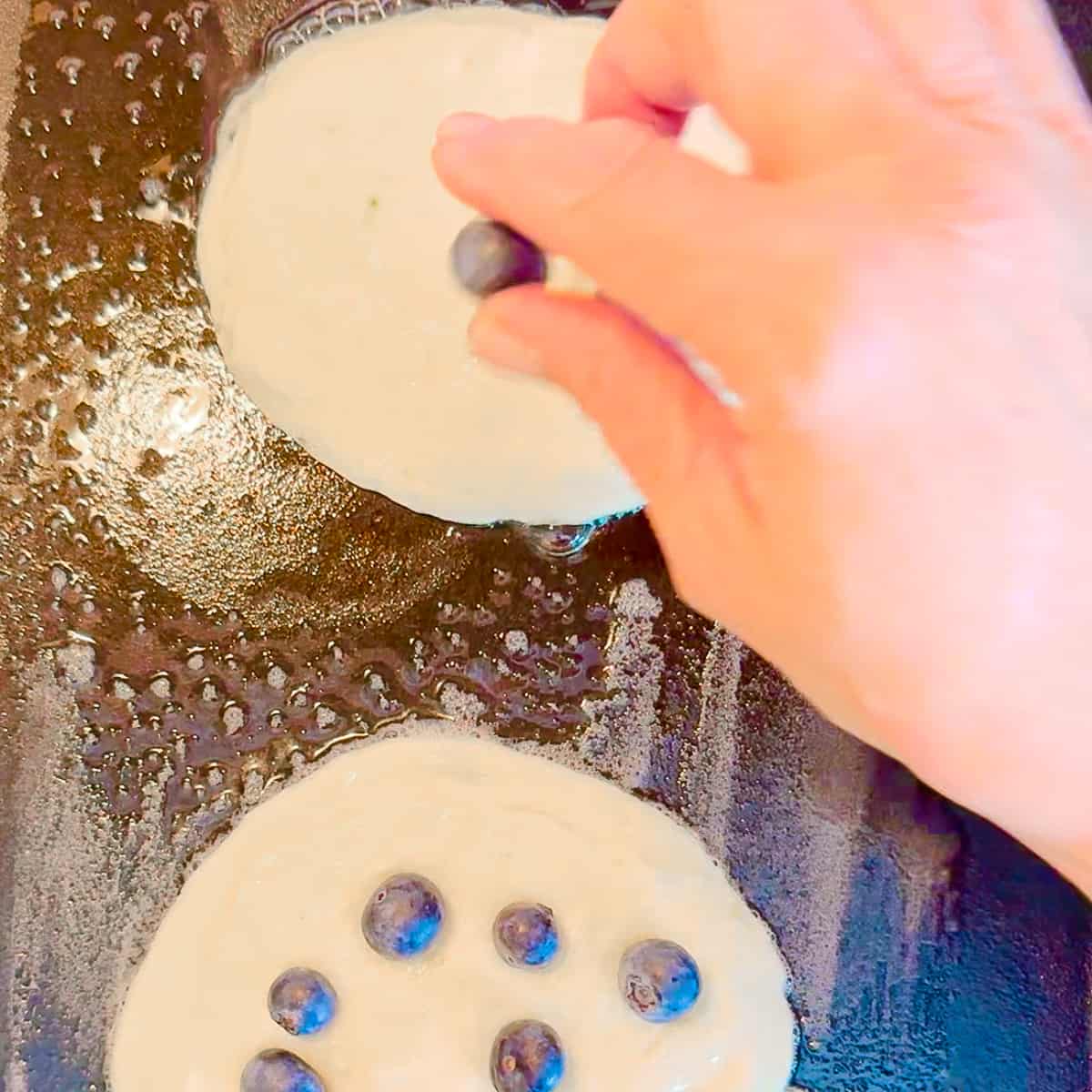 adding blueberries to lemon ricotta pancakes.