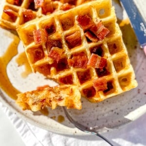 holding a forkful of bacon and cheddar waffles.