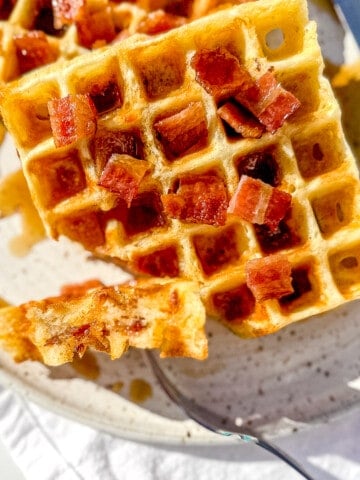 holding a forkful of bacon and cheddar waffles.