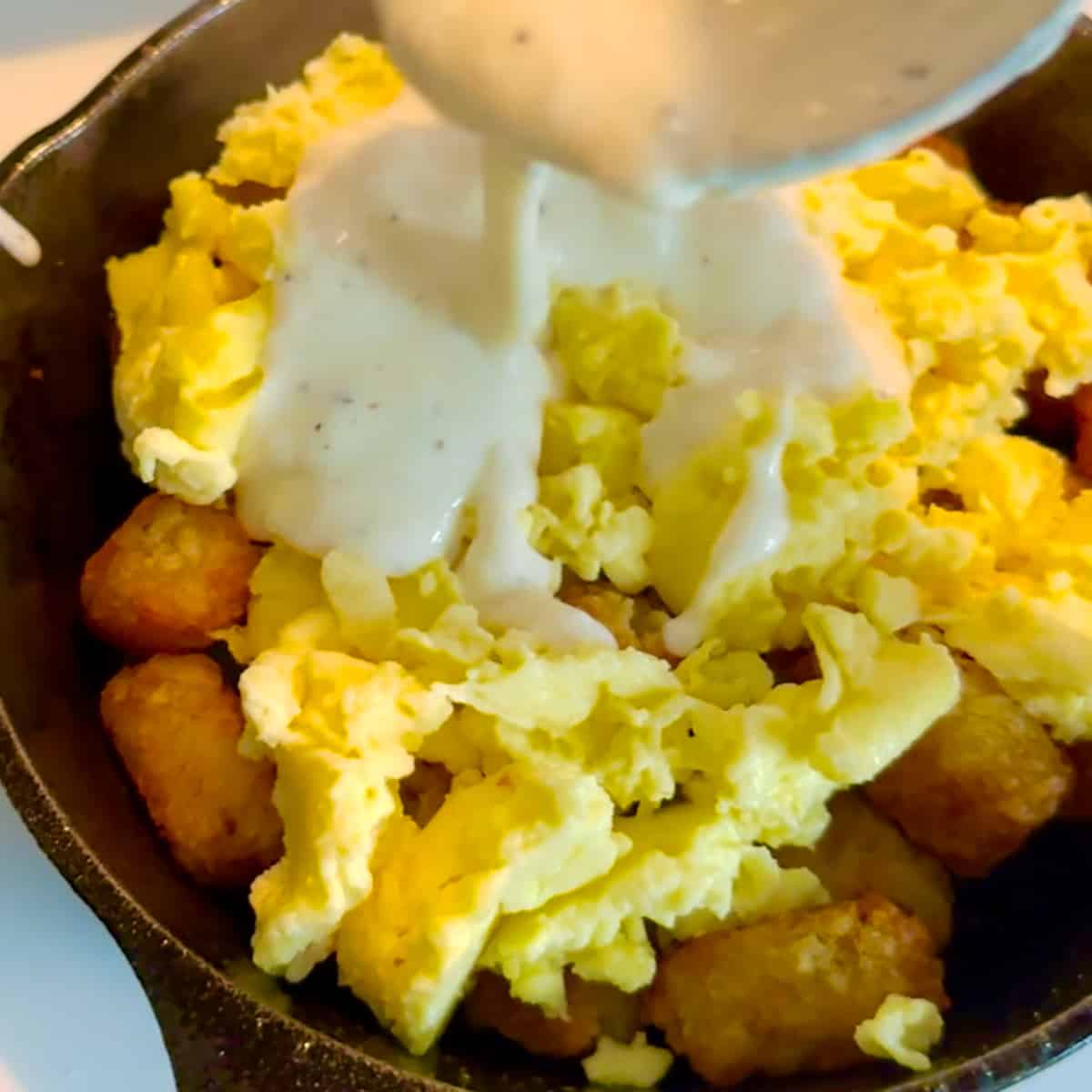 pouring gravy on tater tots and scrambled eggs.