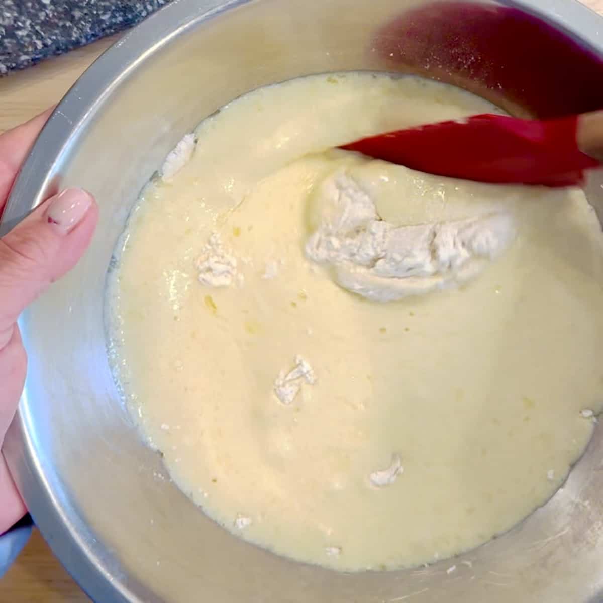mixing waffle batter in a metal bowl.