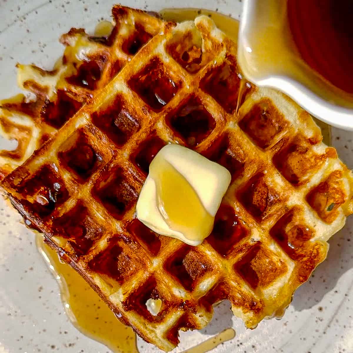 pouring syrup on bacon and cheddar waffles.