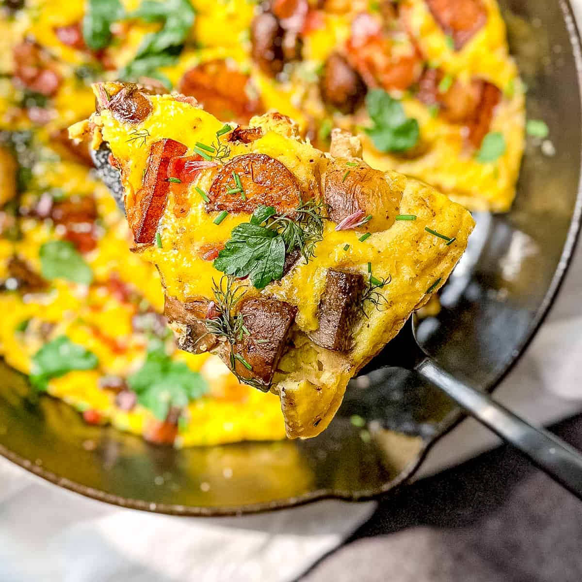 spatula holding a slice of baked country omelette over the pan.