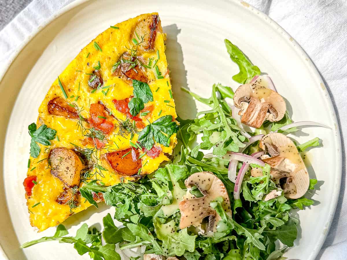 slice of baked country omelette on a plate with a salad.