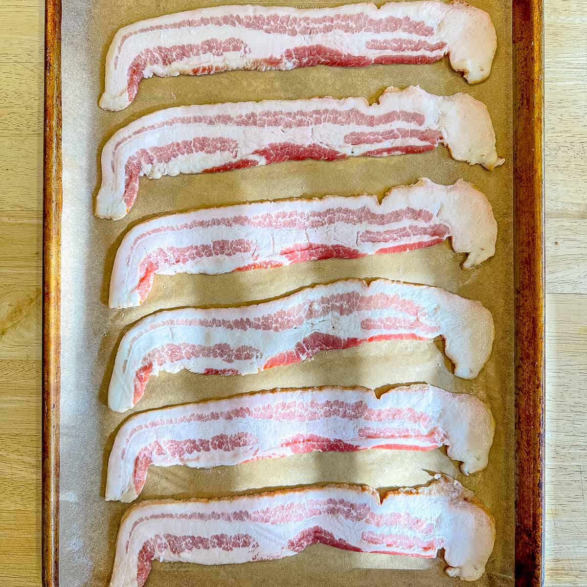uncooked bacon on a sheet pan.