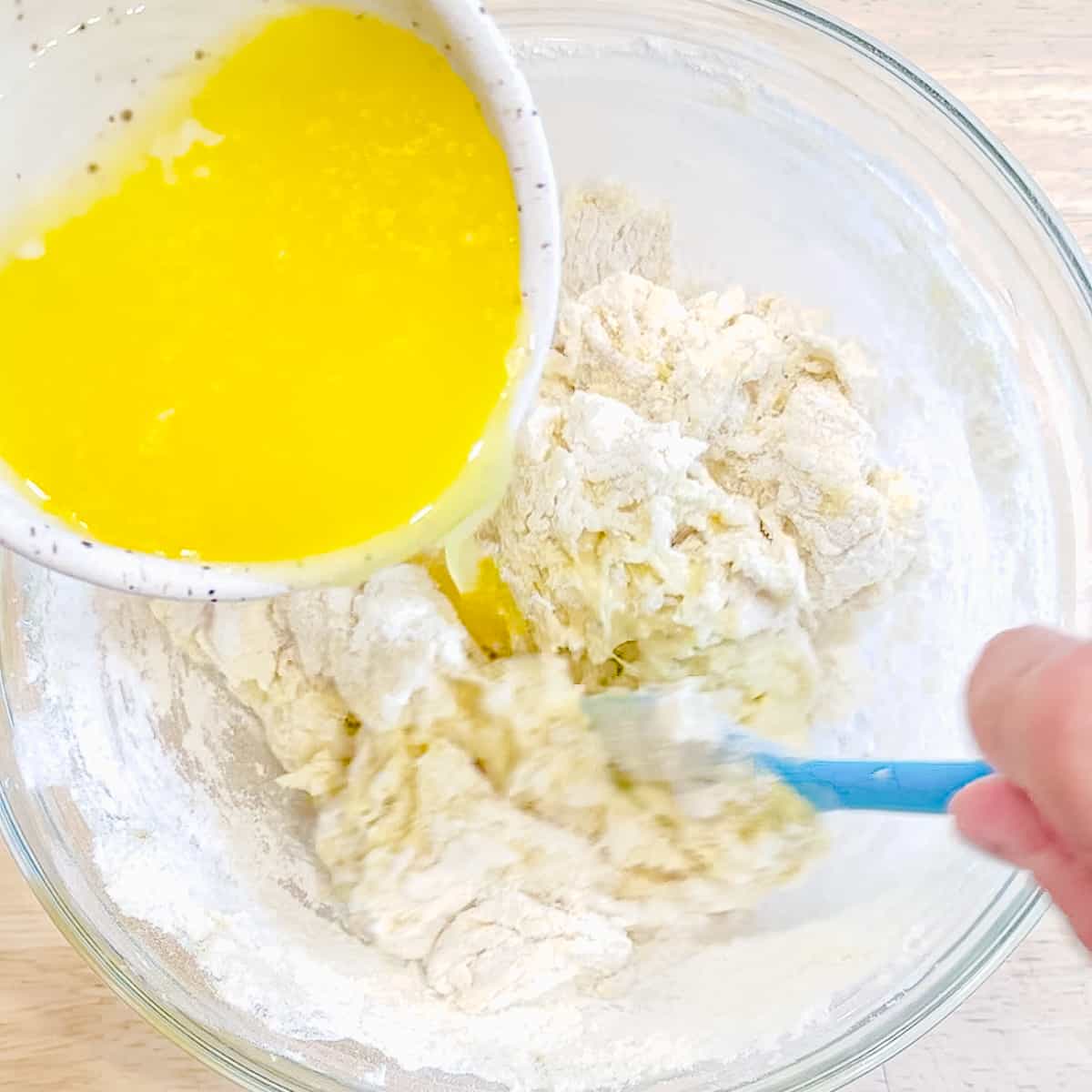 Drizzling melted butter into muffin batter.