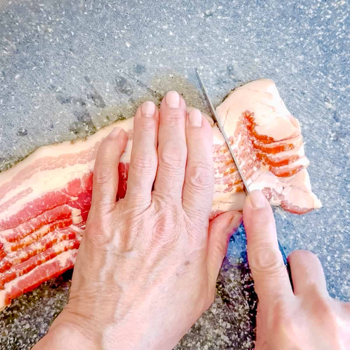 Slicing heavily fatty ends from bacon strips.