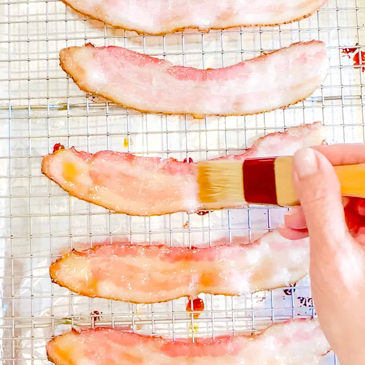 Brushing bacon with maple syrup.
