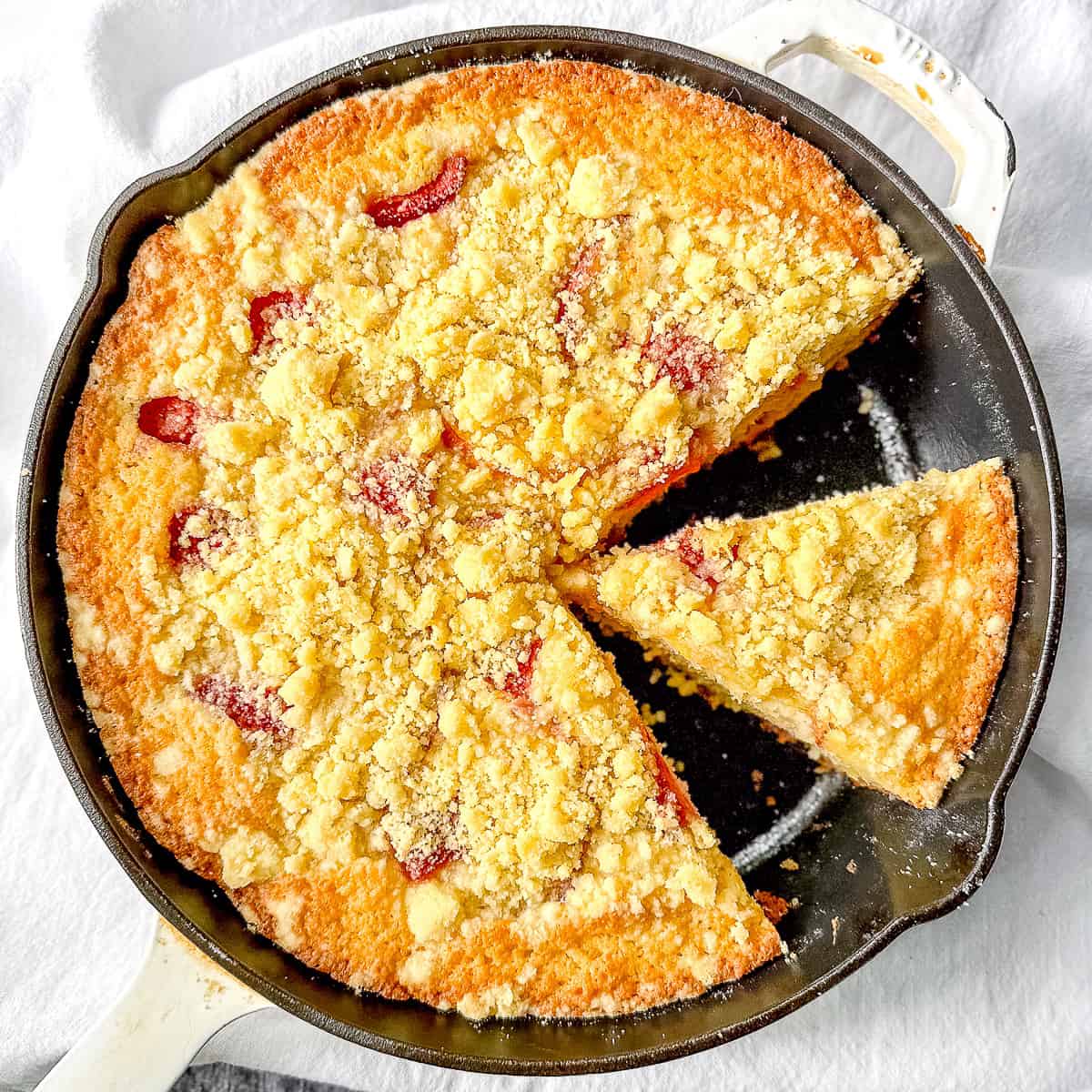 Cast iron pan with sliced strawberry peach buckle.