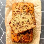 Banana bread on parchment paper on a black tile counter.