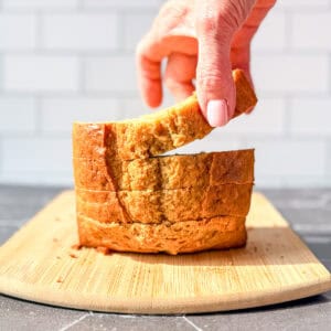 Hand lifting a slice of banana bread from a stack.