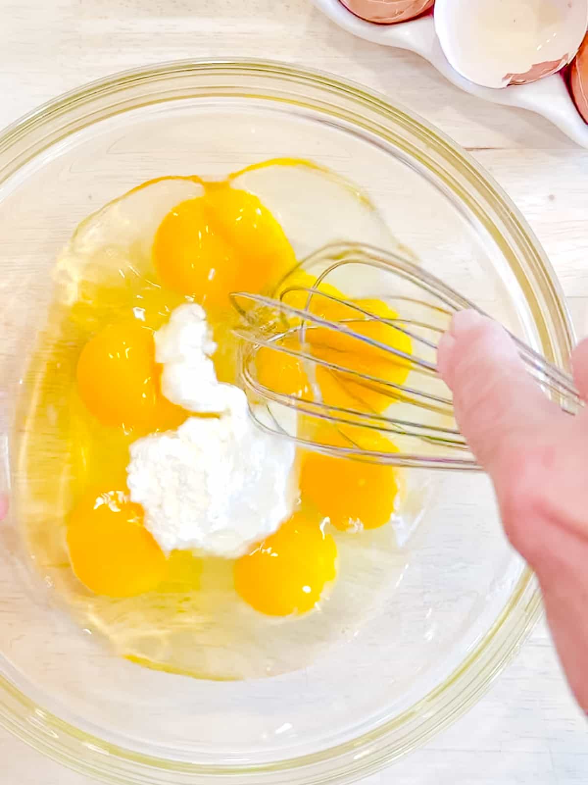 Whisking raw eggs with ricotta cheese.