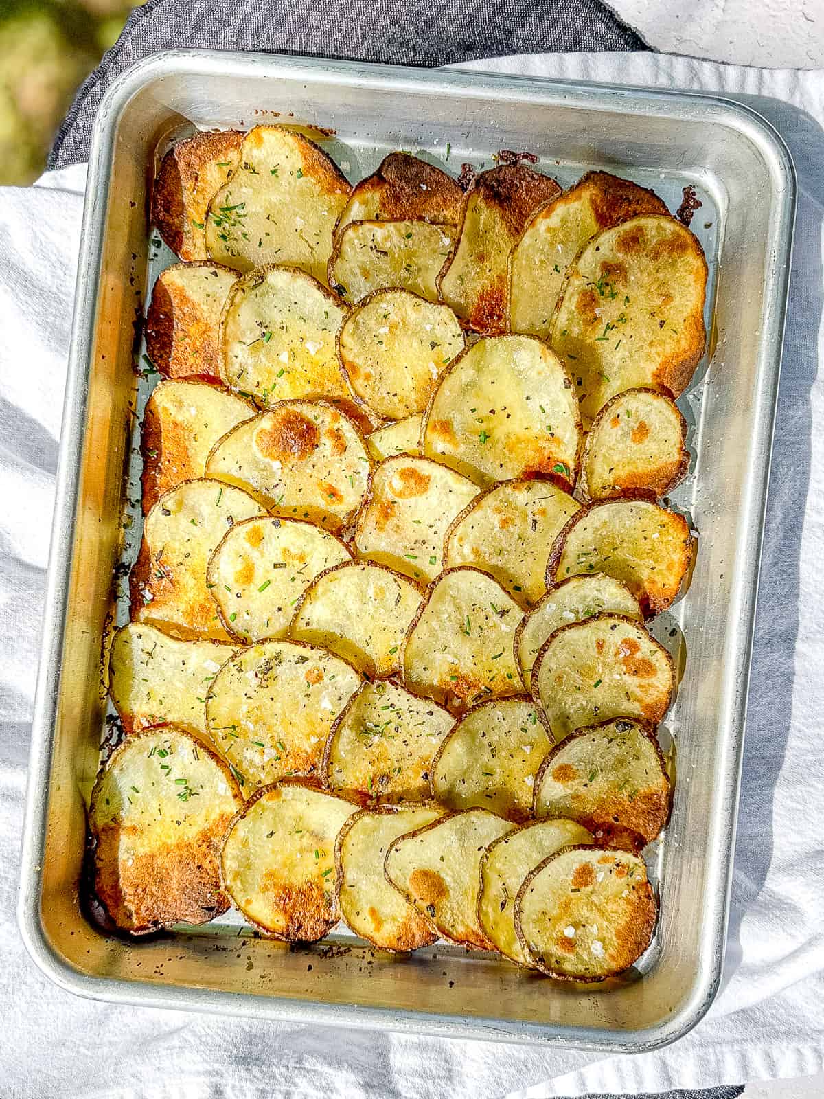 Sheet pan filled with crispy roasted potato slices.