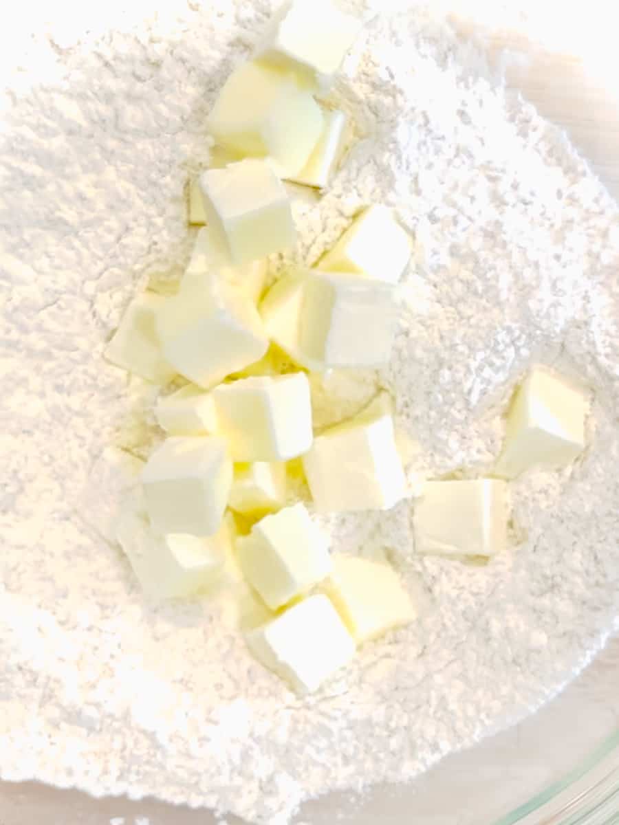 Adding butter to biscuit dry ingredients.