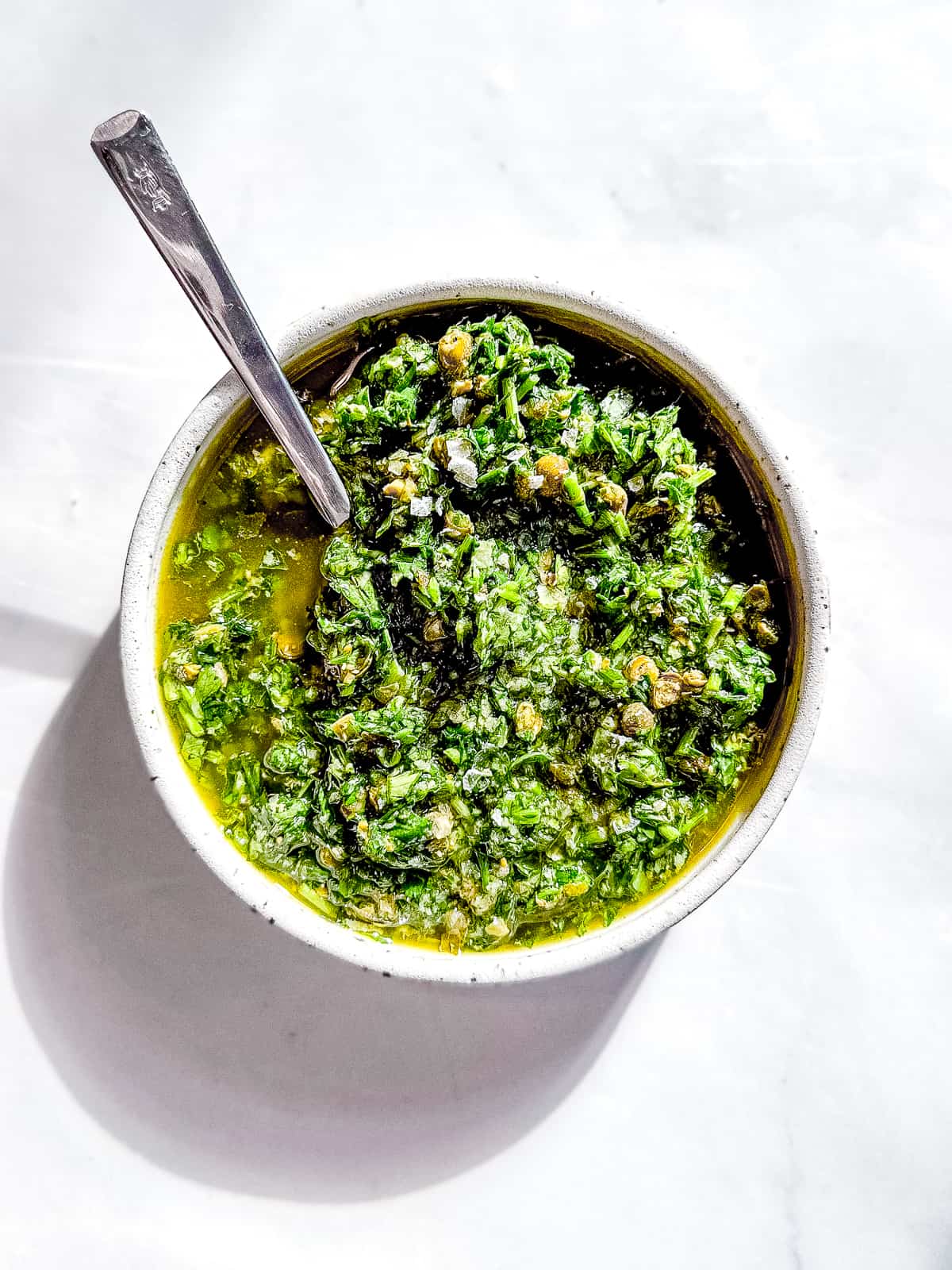 Salsa verde in a bowl with a spoon.
