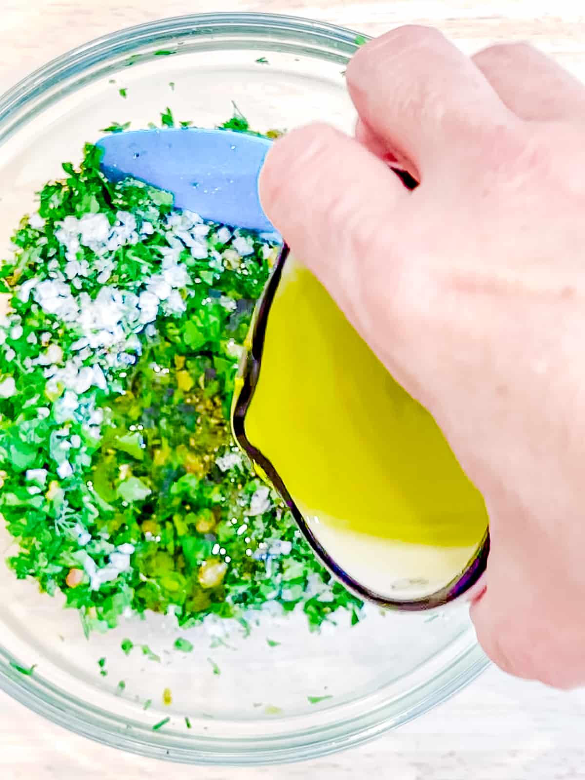 Adding olive oil to herb mixture.