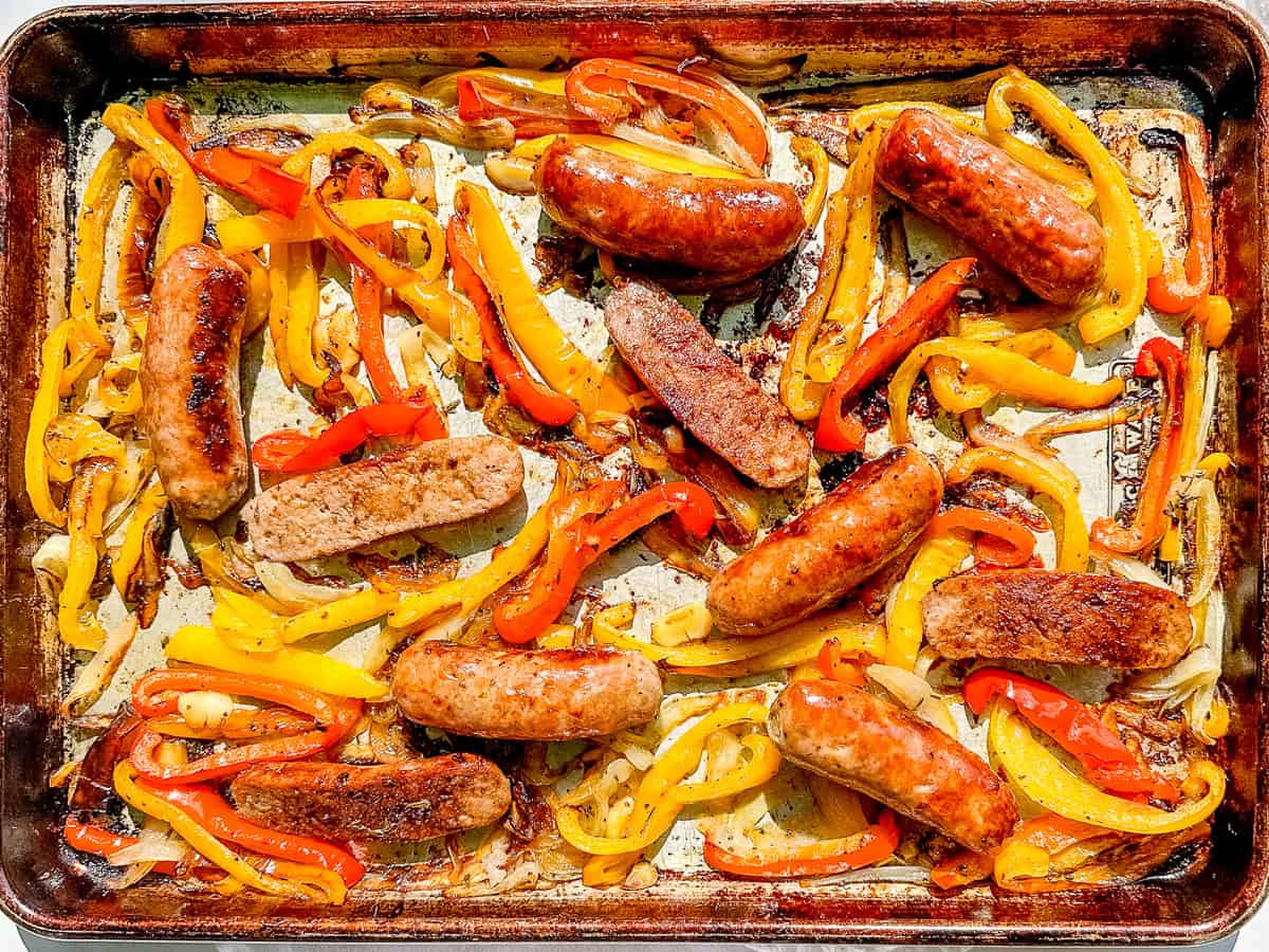 Sheet pan containing roasted sausage and peppers.