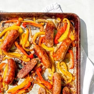 Sheet pan containing roasted sausage and peppers.