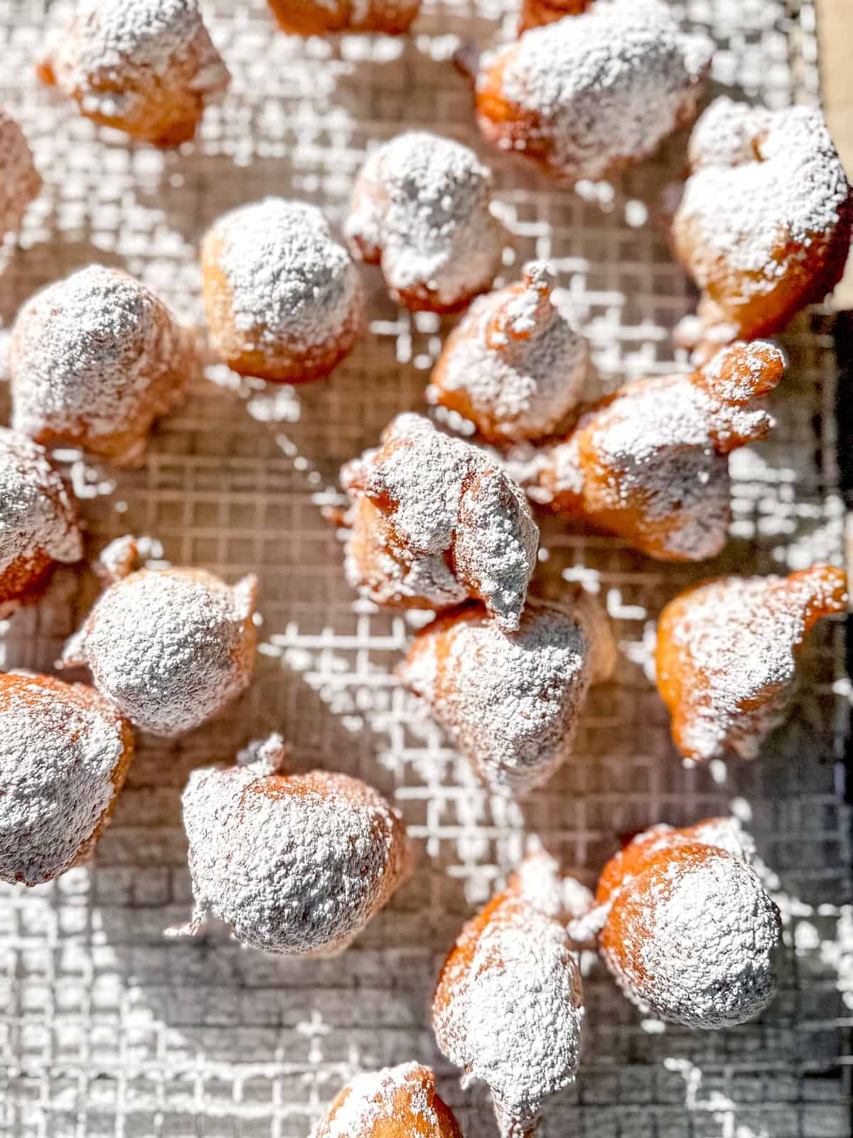 Zeppole with powdered sugar on a wire rack.