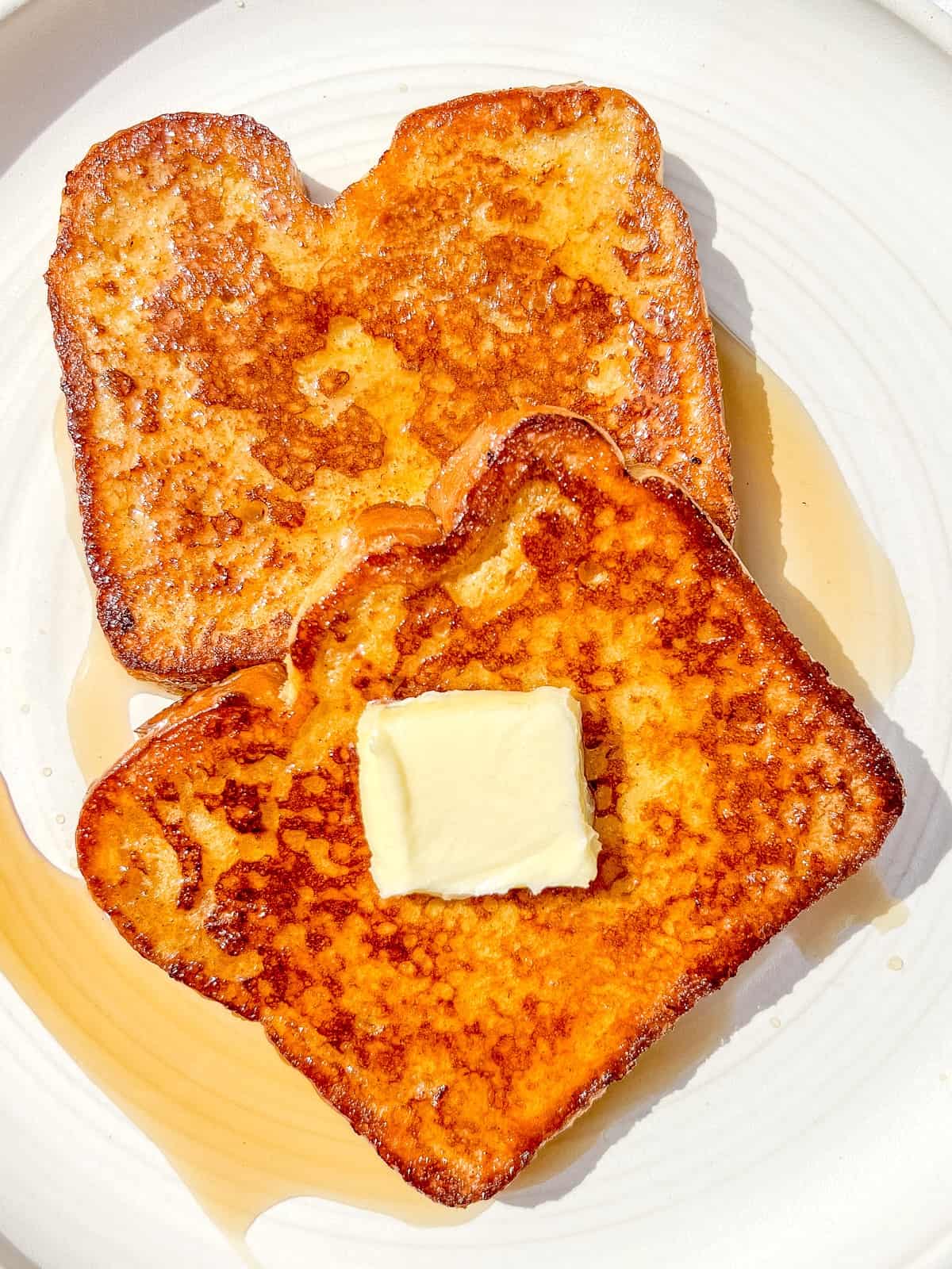 Two slices of cinnamon cardamom french toast on a white plate.