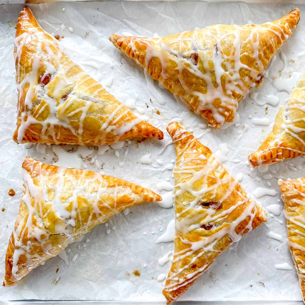 Maple Apple Turnovers on a parchment paper lined sheet pan.