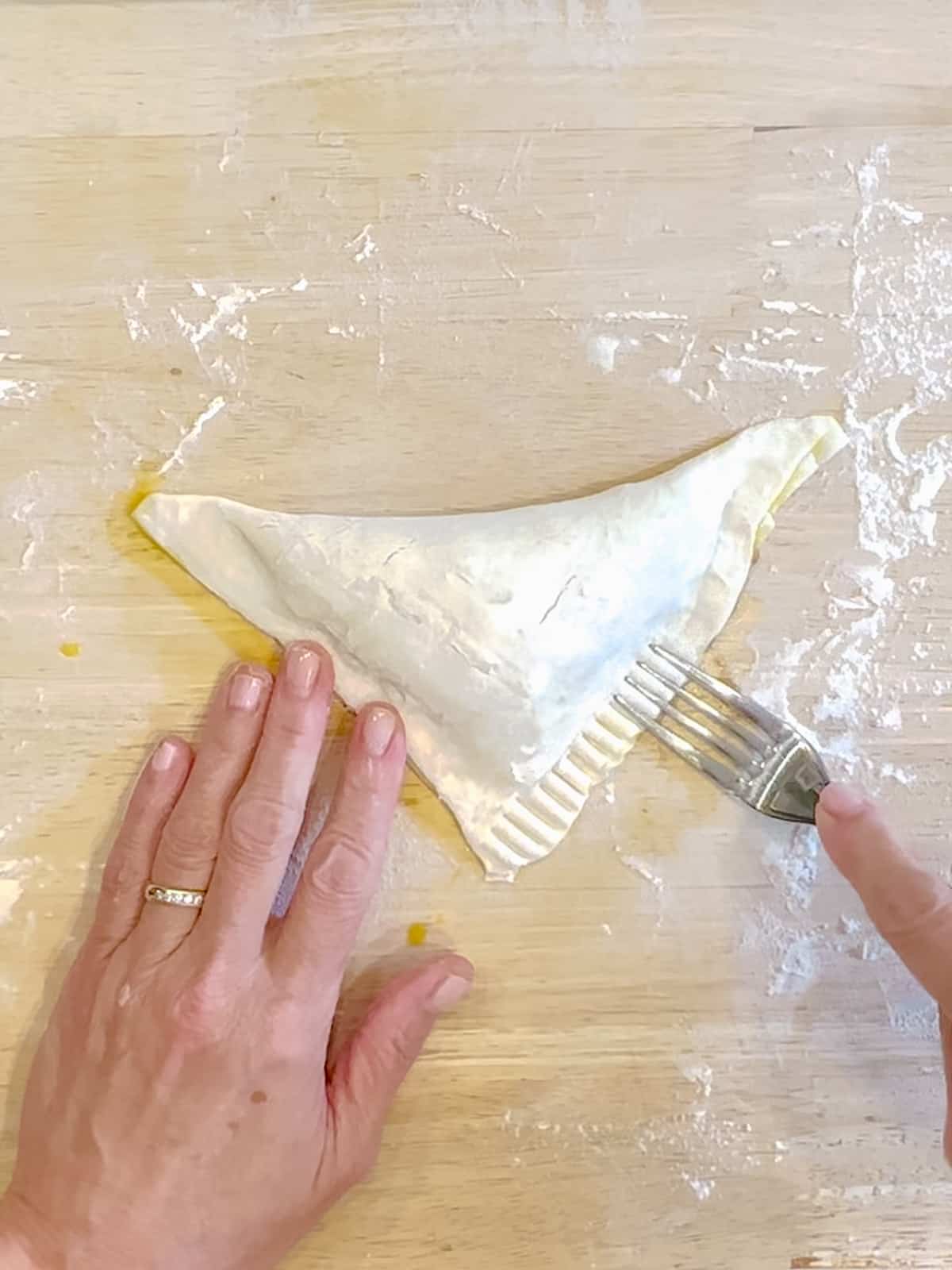 Using a fork to sel the edges of maple apple turnovers.