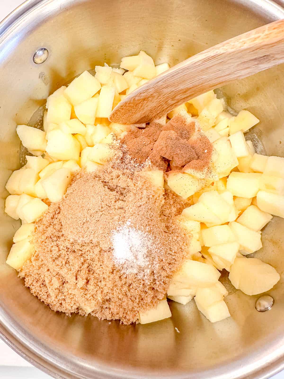 Adding cinnamon and spices to diced apples.